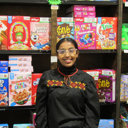 Person standing in front of a cereal aisle with various cereal boxes on shelves.